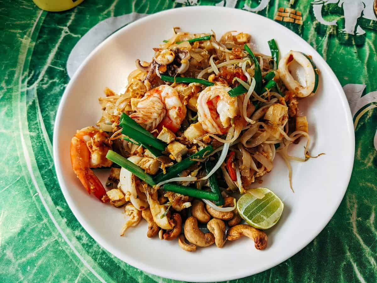 Photo by Markus Winkler Close-up of Pad Thai with shrimp, vegetables, and lime served on a ceramic plate in Bangkok.