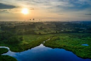 A tranquil aerial landscape of lush countryside and water reflections at sunrise in Banten, Indonesia.